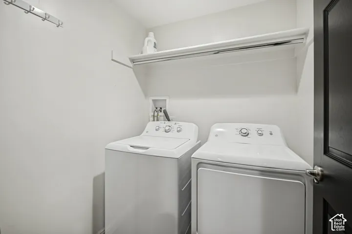 Dedicated laundry area featuring a white built-in shelf, a wall-mounted hanging rack, and a dark paneled door with a brushed nickel knob