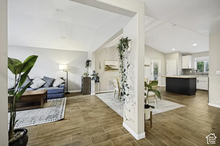 Expansive living area with wood-finish tile flooring, vaulted ceilings, and recessed lighting