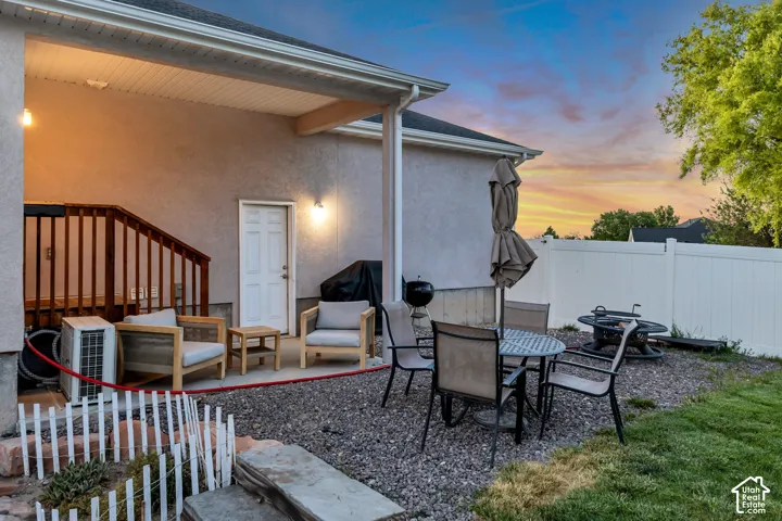 Covered patio area featuring an exterior door, a wooden staircase, and wall-mounted lighting