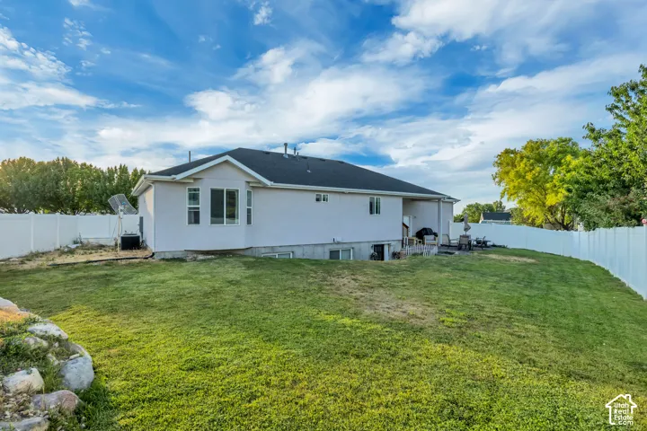 Expansive backyard featuring a lush lawn, privacy fencing, and a stucco exterior