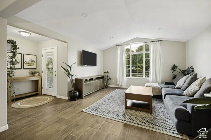 Spacious living area featuring wood-finish flooring and a vaulted ceiling with recessed lighting