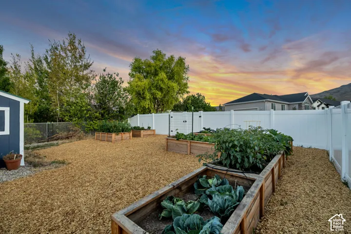 Spacious backyard featuring multiple raised garden beds, a dedicated gravel pathway, and a privacy fence
