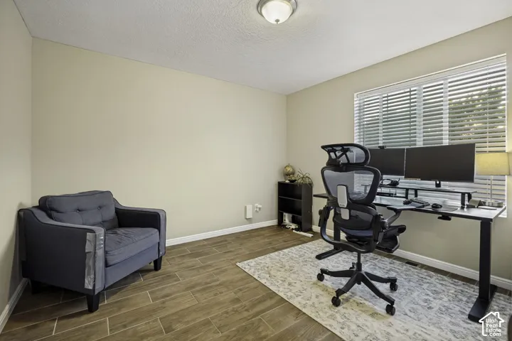 Room featuring wood-finish flooring, neutral wall tones, and a window with horizontal blinds