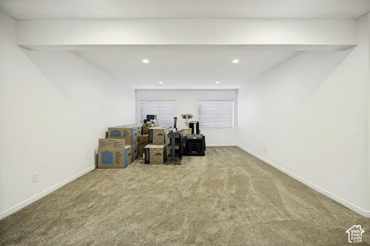 Spacious room featuring neutral carpeting, recessed lighting, and two windows with horizontal blinds