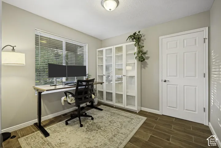 Versatile room featuring wood-finish flooring, a large window with blinds, and built-in glass-front cabinetry