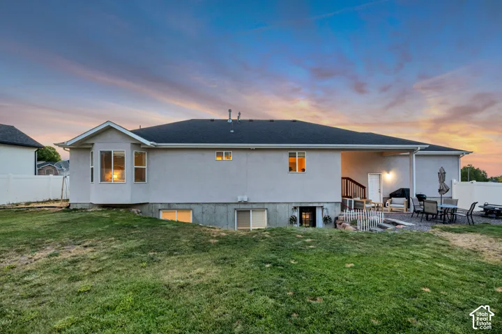 Expansive grassy yard surrounding a stucco exterior with a covered patio, walk-out basement access, and bay windows