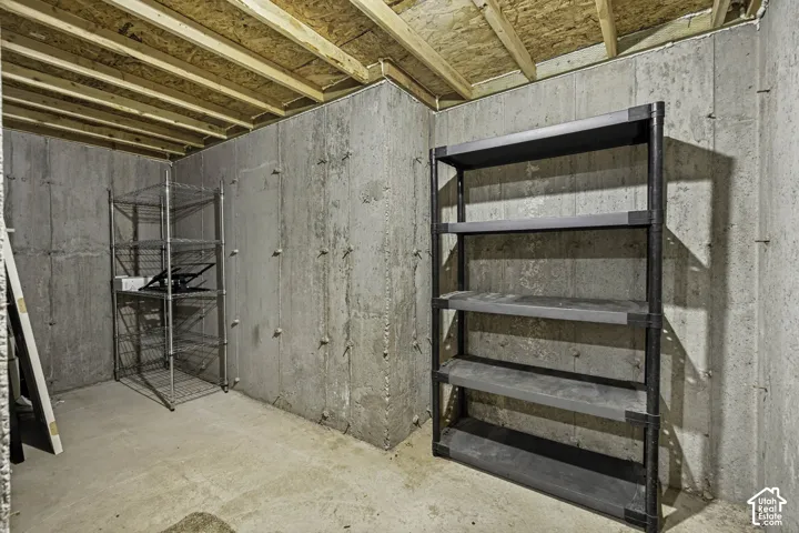 Unfinished basement space featuring exposed concrete walls and ceiling joists