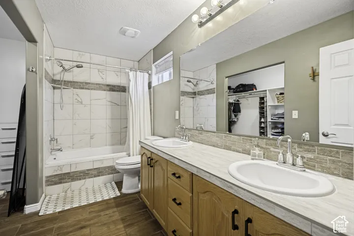Bathroom featuring a dual vanity with oak cabinetry, wood-finish countertops, and chrome fixtures