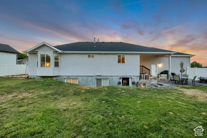 Expansive backyard featuring a covered patio, gravel hardscaping, and a terraced lawn
