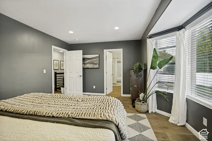 Bedroom featuring recessed lighting, a bay window with blinds, wood-finish flooring, and two doorways providing access to other areas