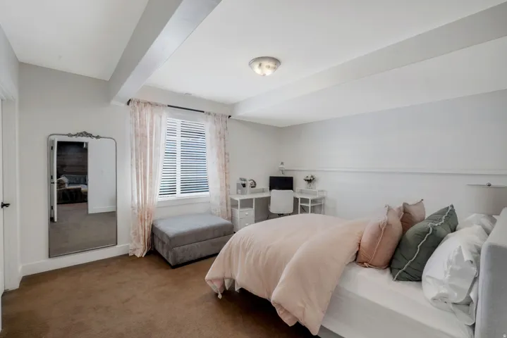 Carpeted room featuring a window with white blinds, a ceiling light fixture, and exposed ceiling beams