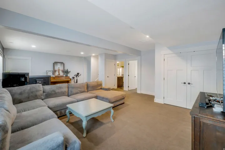 Carpeted recreation room featuring recessed lighting, light gray walls, white baseboards, and white panel doors