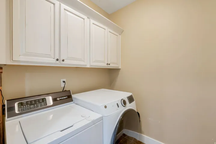 Laundry area featuring upper white cabinetry with dark hardware and a light-toned wall finish
