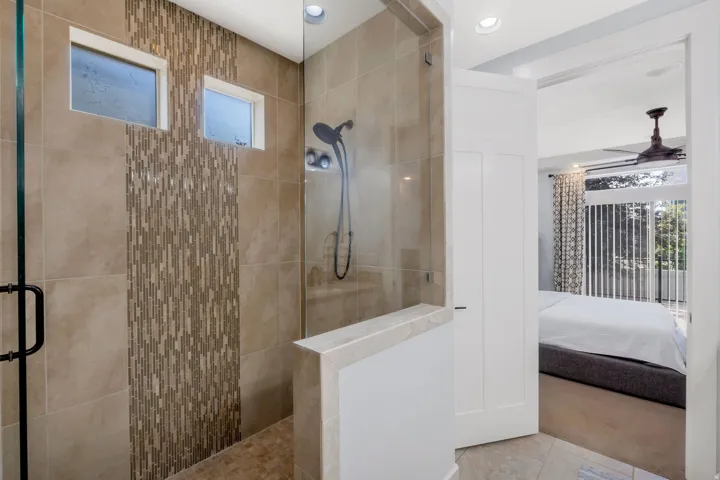 Glass-enclosed shower featuring large format tile and a mosaic accent wall, complete with a built-in bench and recessed lighting