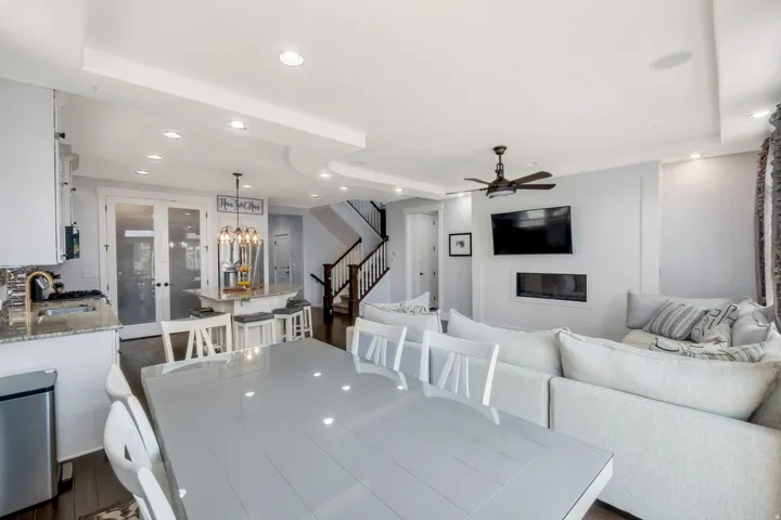 Open-concept living area featuring dark wood-finish flooring, recessed lighting, a built-in linear fireplace, and a ceiling fan