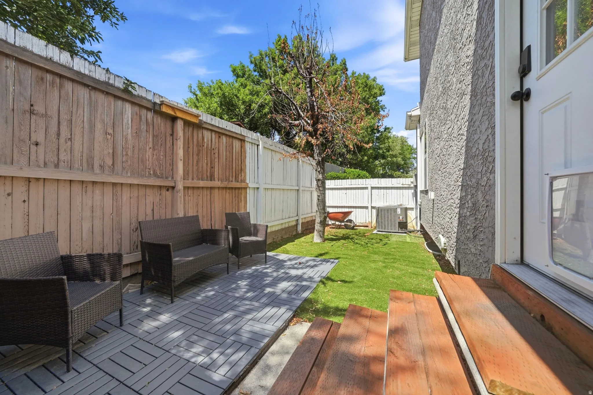 Private fenced yard featuring a patio area with interlocking pavers, a manicured lawn, and a stucco exterior