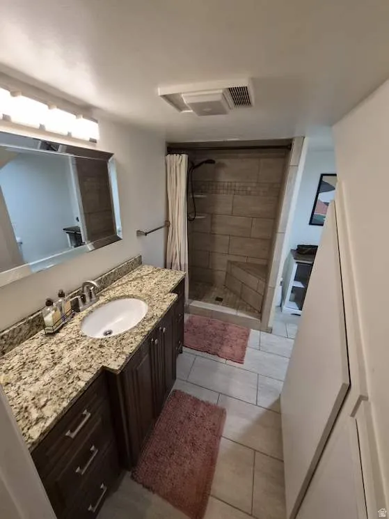 Bathroom featuring a spacious vanity with a granite-finish countertop, undermount sink, and dark wood cabinetry