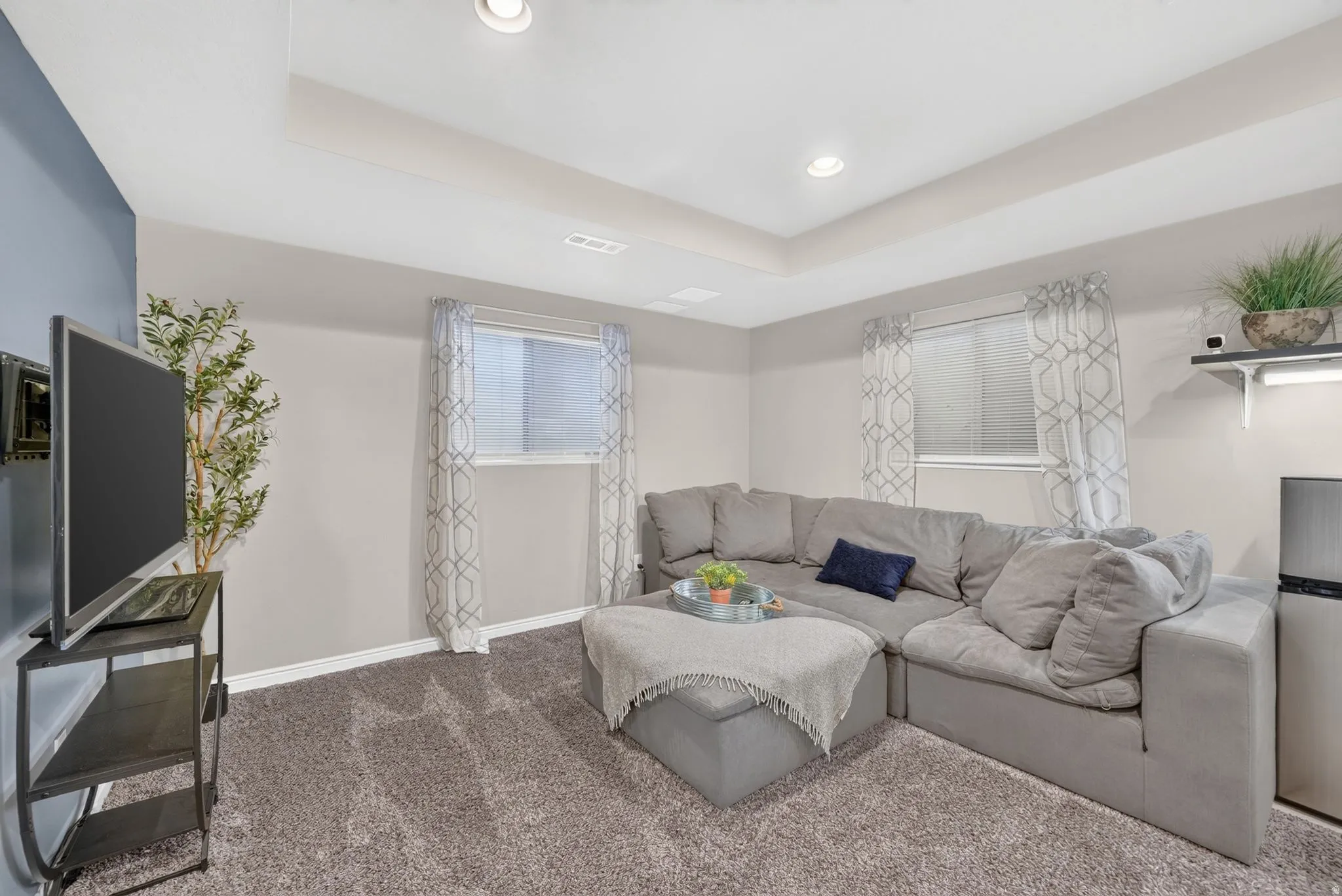 Carpeted room featuring a recessed tray ceiling with integrated lighting