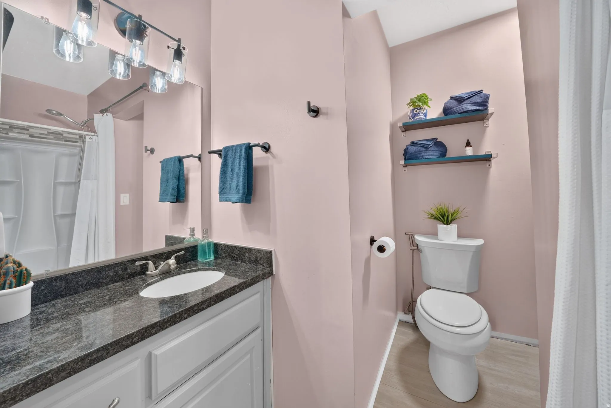 Bathroom featuring a white vanity with an integrated sink, dark granite-style countertop, and a vanity mirror