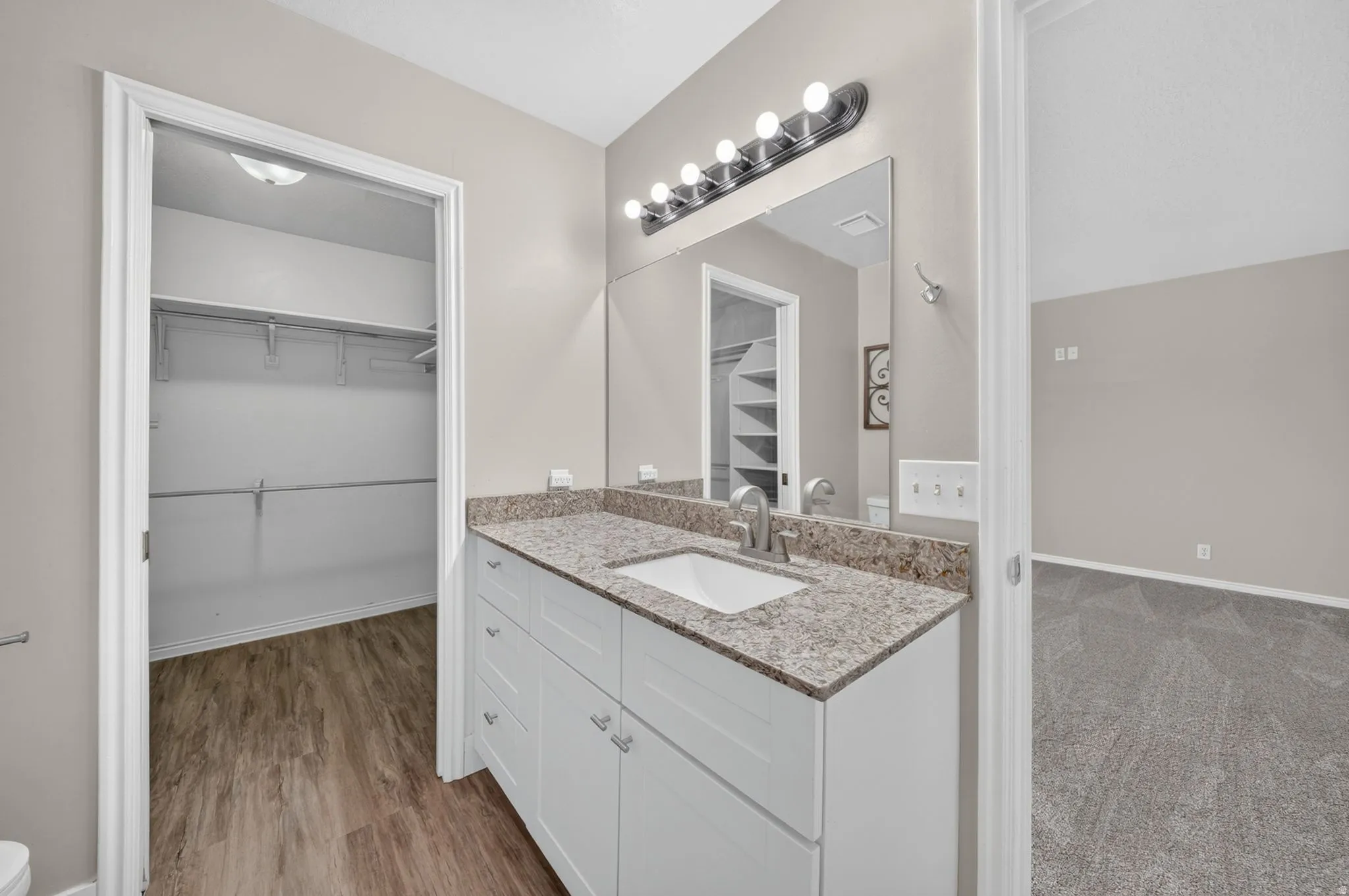 Bathroom vanity with a granite countertop, undermount sink, and brushed nickel faucet