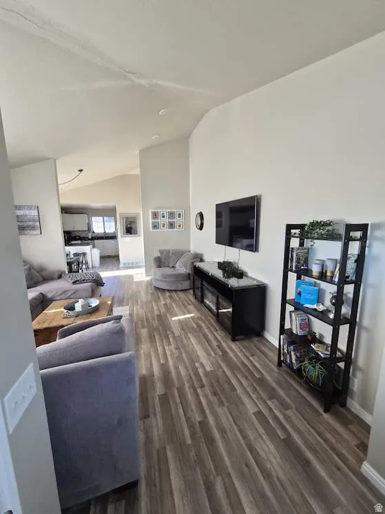 Open-concept living area with wood-finish flooring, vaulted ceilings, and recessed lighting