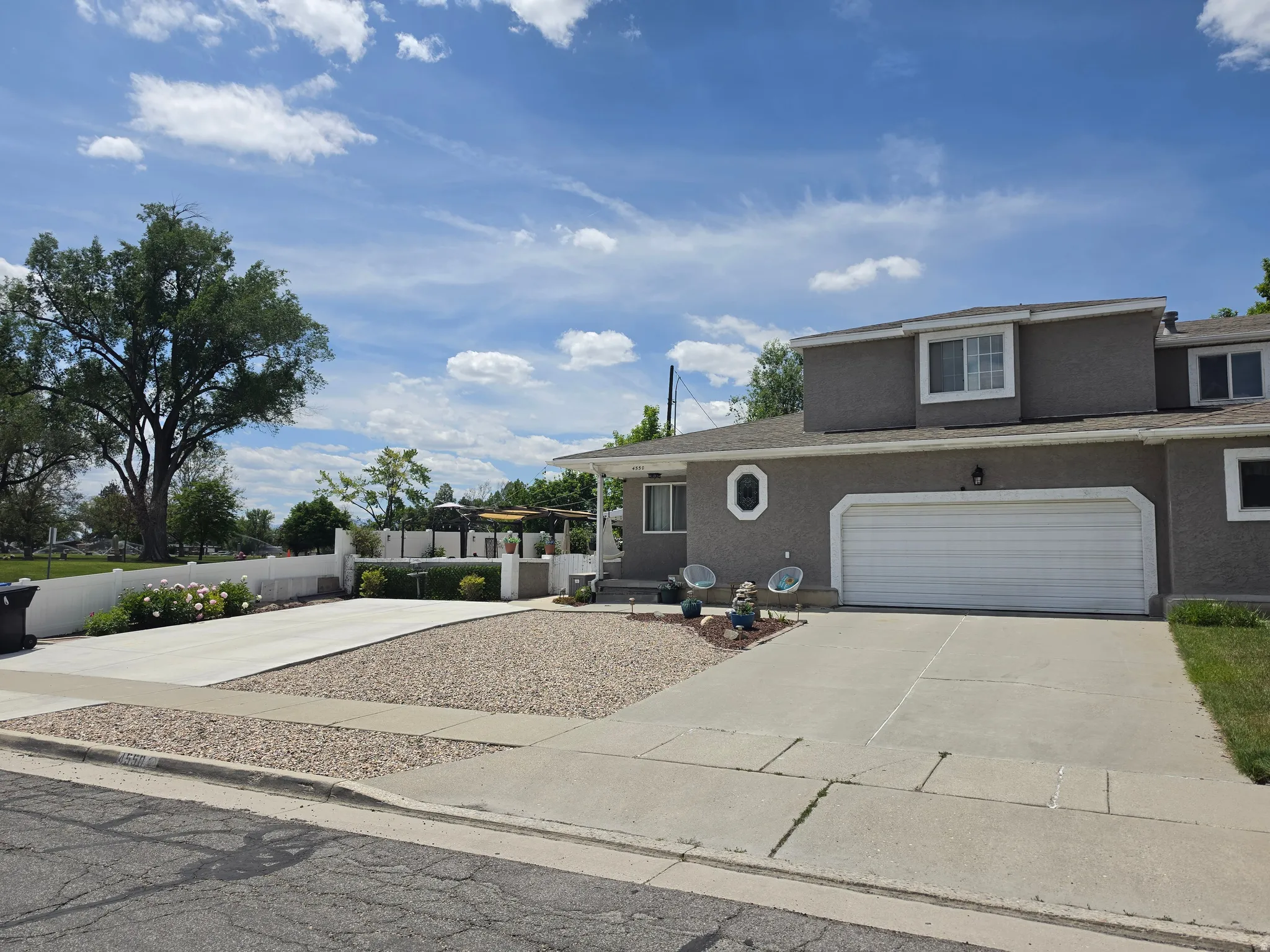 Two-story stucco exterior featuring an attached two-car garage, a concrete driveway, and a gravel front yard