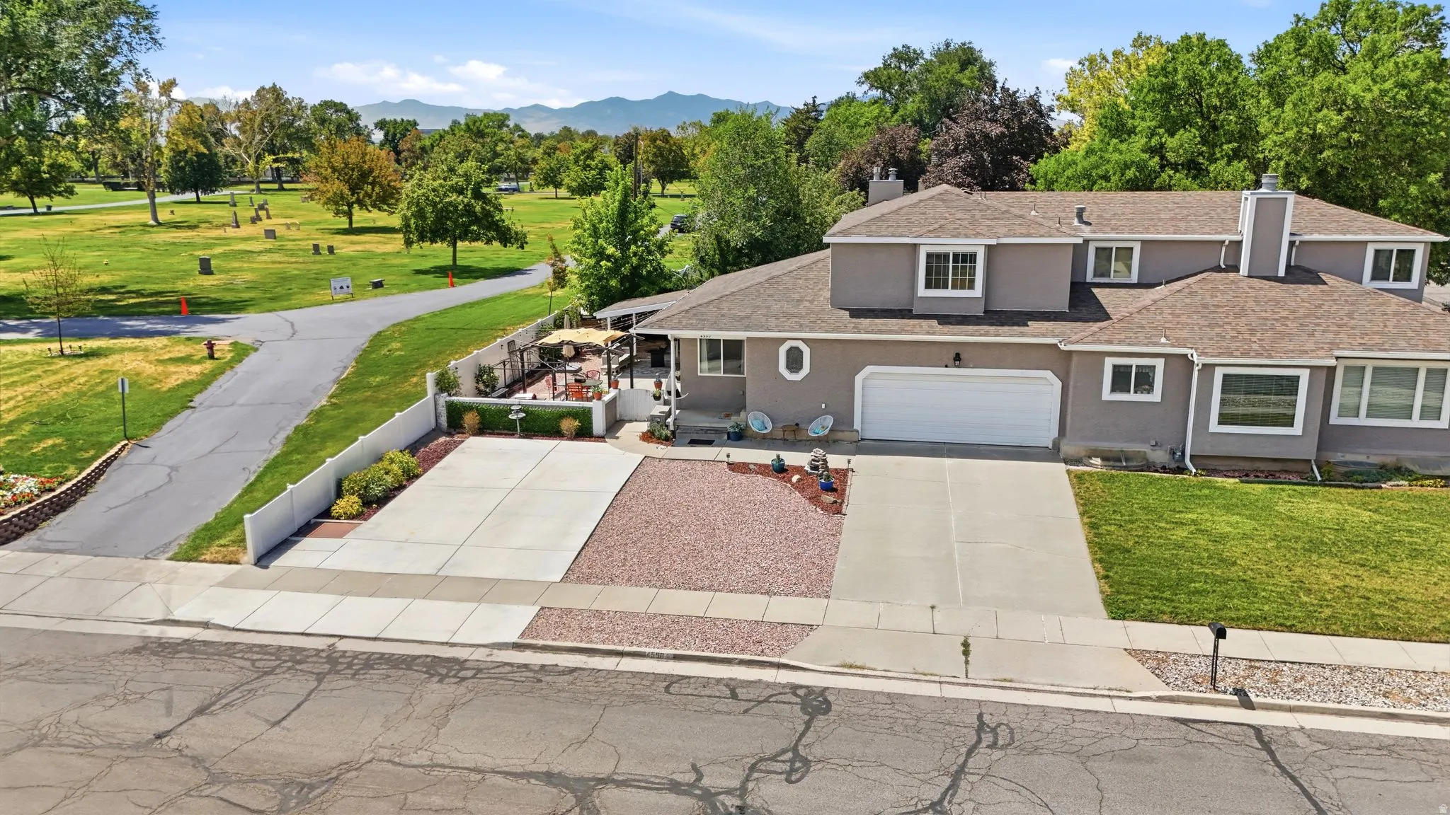 Two-story stucco residence featuring a two-car garage, multiple driveways, and a covered back patio
