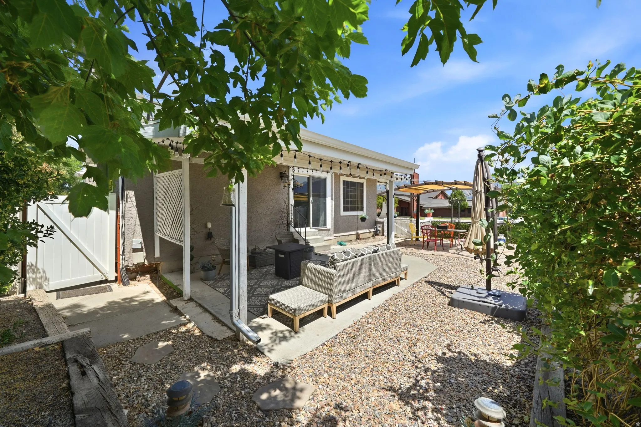 Private outdoor patio area featuring a covered porch, sliding glass door access, and a gravel ground cover