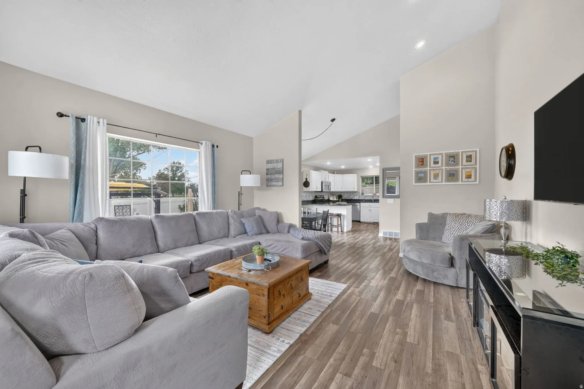 Spacious living area featuring vaulted ceilings and wood-finish flooring