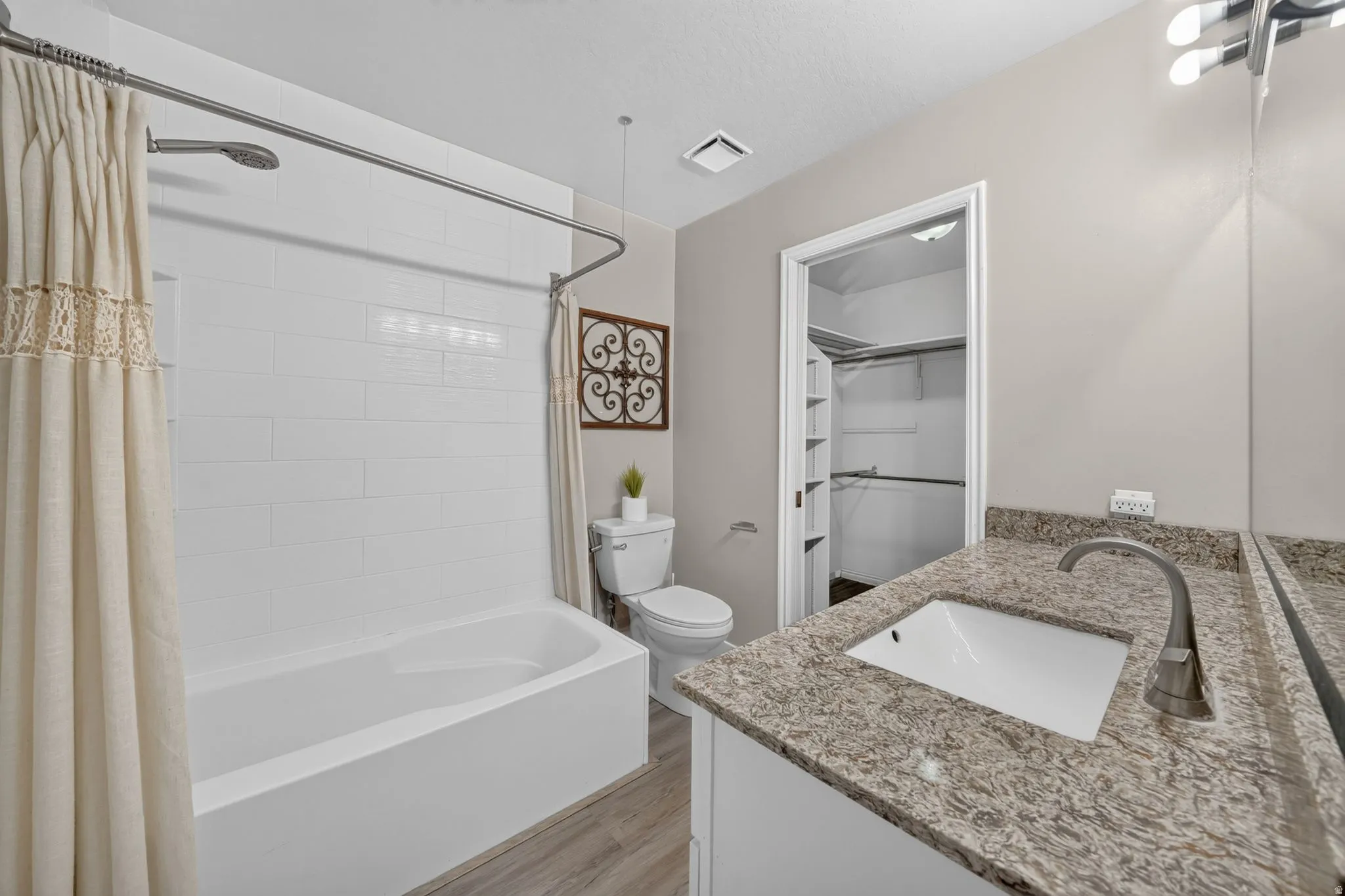 Bathroom featuring a single vanity with stone-finish countertop, undermount sink, and brushed nickel faucet