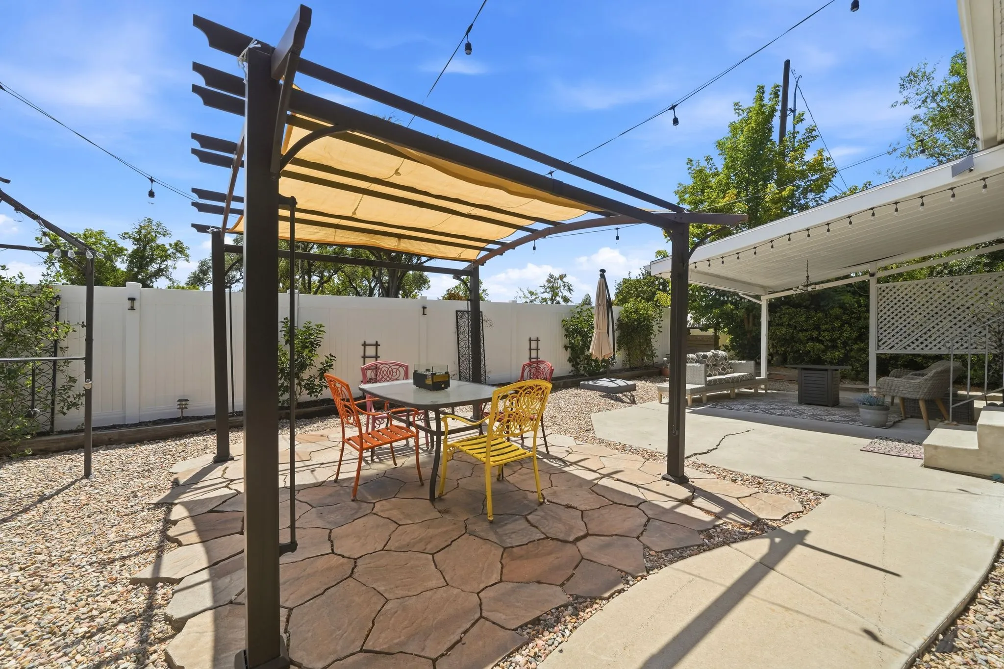 Expansive outdoor patio featuring a pergola with a retractable shade canopy and flagstone flooring