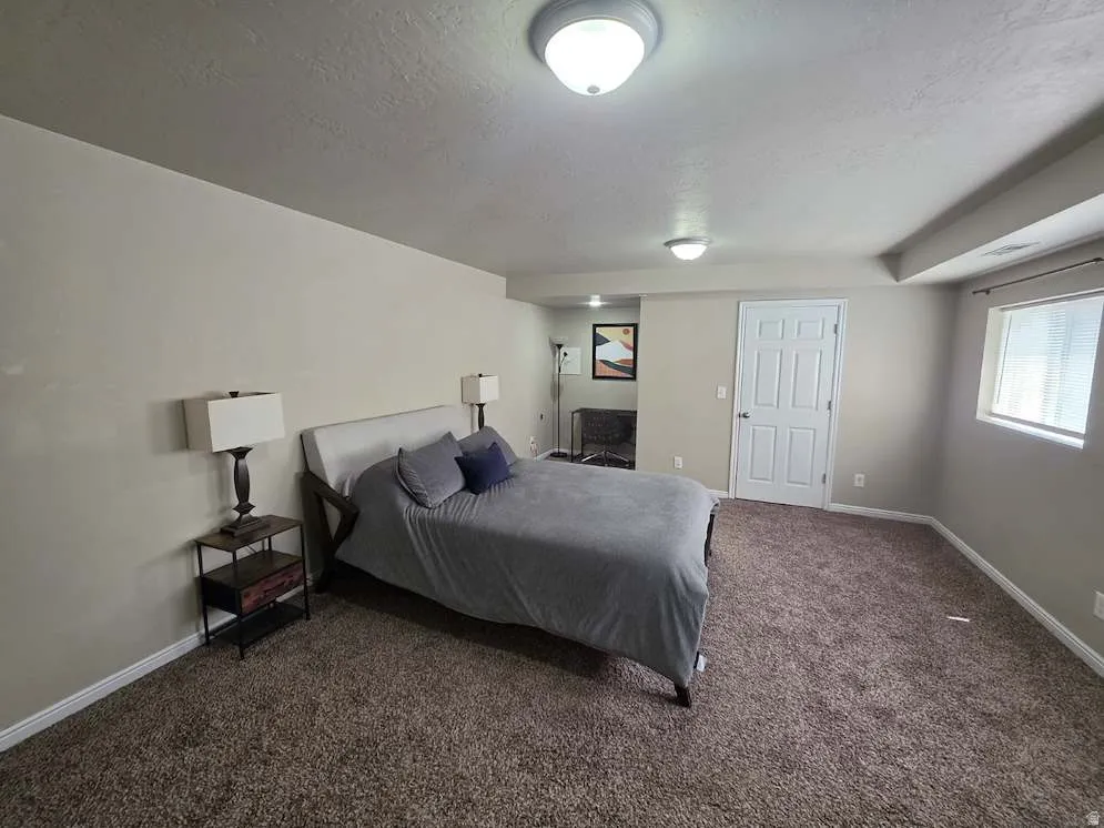 Spacious room featuring neutral paint, brown carpeting, baseboard trim, and a window with blinds