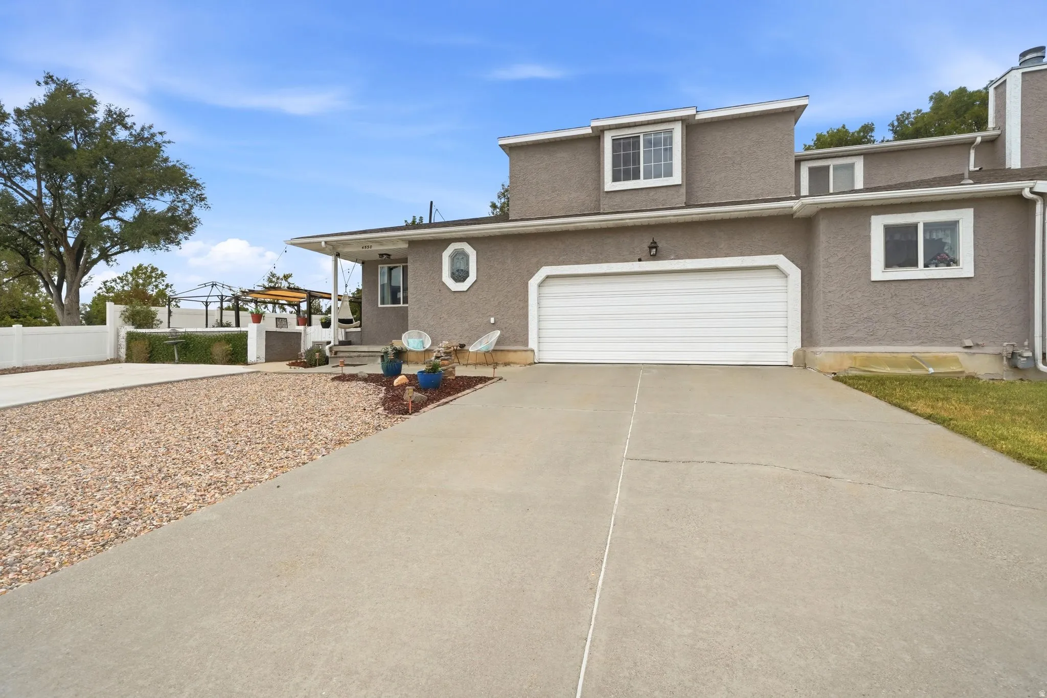 Stucco exterior featuring a two-car garage, concrete driveway, and dormer windows