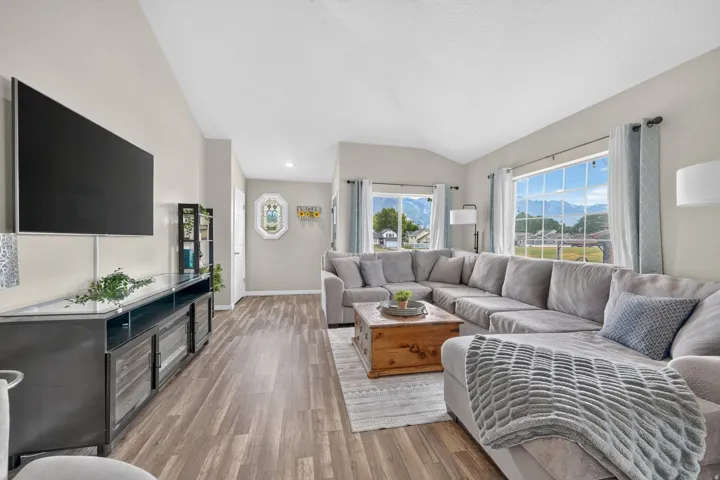 Expansive living area with wood-finish flooring, vaulted ceilings, and large windows
