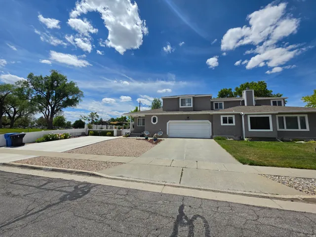 Stucco exterior featuring multiple window styles, an attached garage, a concrete driveway, and a gravel accent strip