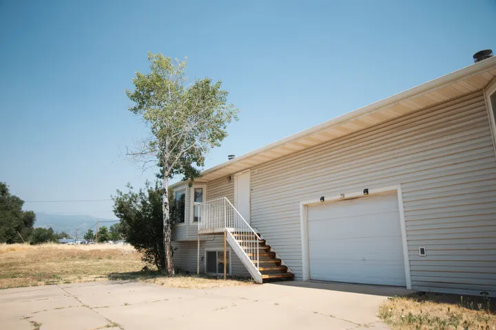 Exterior showcasing light-colored horizontal siding, a two-car garage, and an upper-level entry with white railings