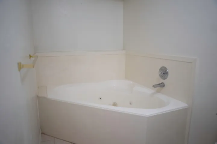 Corner jetted tub with white surround and chrome fixtures