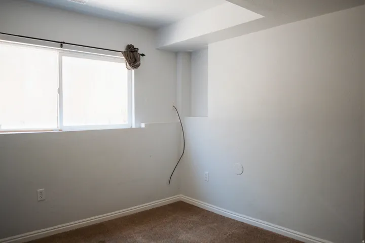 Recessed window with white frame, neutral carpeting, white baseboards, and white painted walls