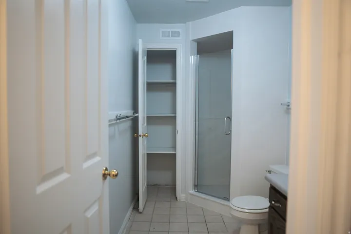 Bathroom featuring a glass-enclosed shower, white toilet, and built-in shelving