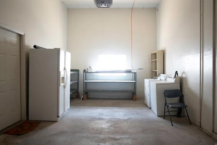 Spacious utility area featuring a concrete floor, light-toned walls, and a white interior door