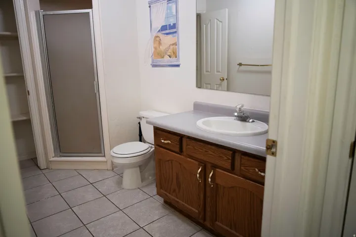 Bathroom featuring a wood vanity with a laminate countertop, an integrated sink, and a framed mirror