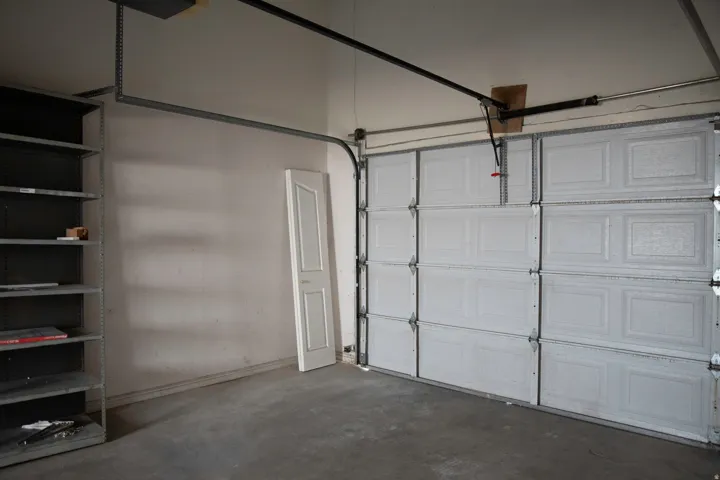 Interior garage featuring a paneled overhead door, concrete flooring, and an integrated shelving unit
