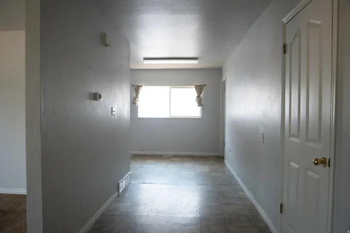 Hallway featuring light gray walls, white trim, and a paneled door with brass hardware