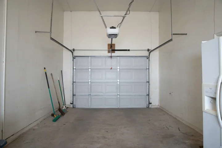 Single-car garage featuring a paneled overhead door, concrete flooring, and an automatic garage door opener