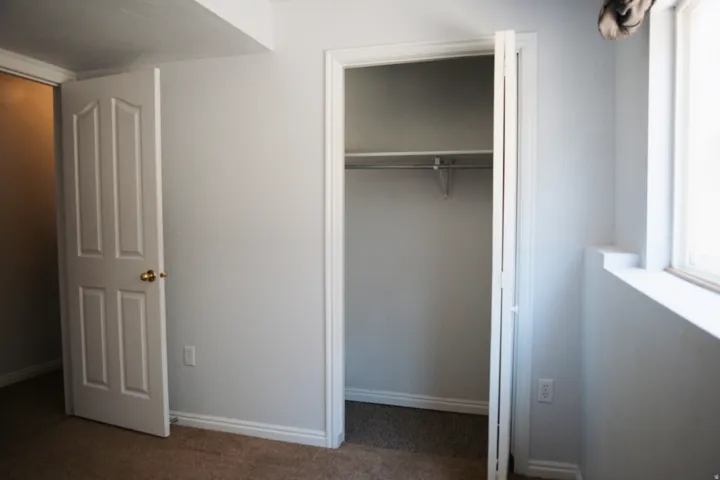 Interior room featuring neutral wall paint, carpet flooring, a bifold closet door, and a standard window