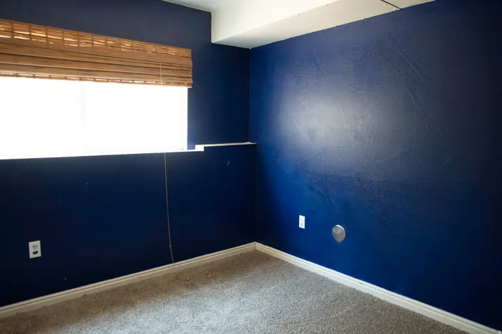 Room featuring blue painted walls, neutral carpet flooring, and white baseboards