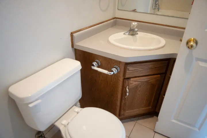 Bathroom vanity featuring a corner countertop, an integrated sink, and wood-finish cabinetry with silver-tone hardware