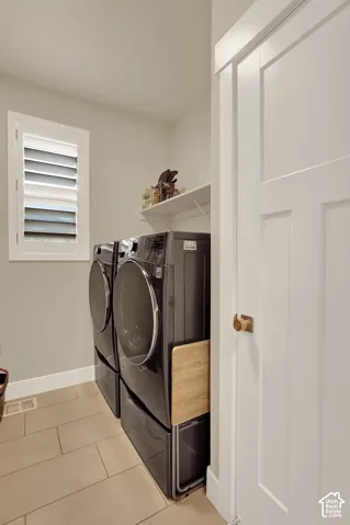 Utility space with tiled flooring, white baseboards, and a window with plantation shutters