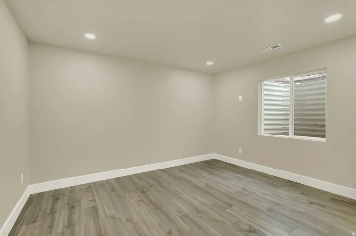 Spacious room featuring wood-finish flooring, recessed lighting, and a neutral wall color
