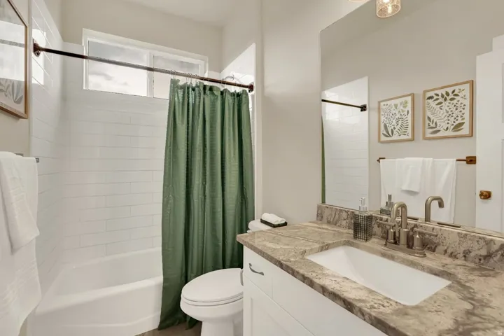 Bathroom featuring a single vanity with a stone-finish countertop, undermount sink, and brushed nickel faucet